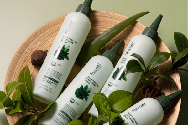 Aloe Vera for Itchy Scalp Routine Four bottles of Mayraki scalp treatment products are arranged in a wooden bowl with fresh aloe vera leaves and green foliage. The sleek white bottles feature natural leaf graphics, reinforcing the brand’s focus on soothing, plant-based solutions for scalp care, including relief from itchiness.