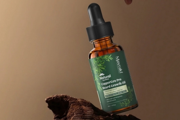 A bottle of Mayraki CopperGro Pro Beard Growth Oil resting on textured wood, featuring a green label and dropper cap, promoting the importance to Apply beard oil daily for moisture, strength, and post-trim care.