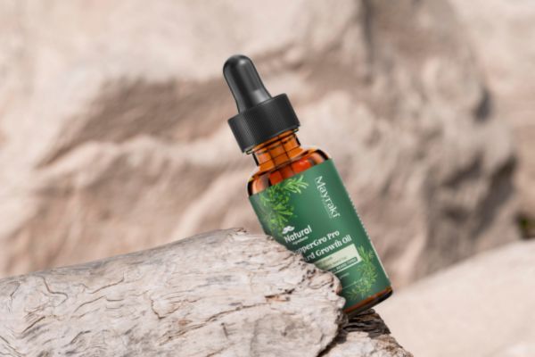 A bottle of Mayraki CopperGro Pro Beard Growth Oil rests on weathered driftwood with a soft-focus rock background. The amber glass bottle and green label emphasize a natural, earthy vibe.