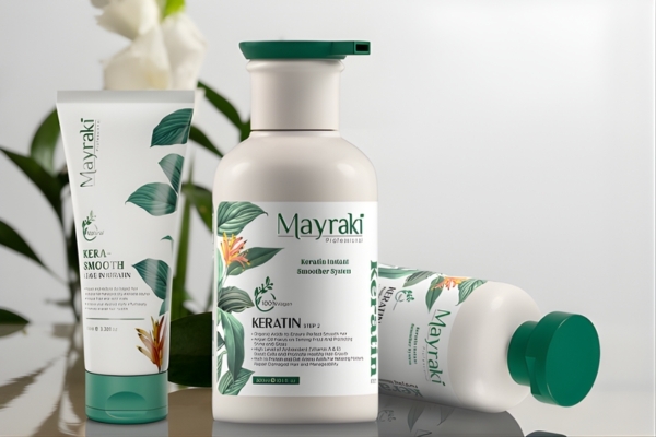 Three Hair Mayraki products from the Keratin Smooth line are displayed on a reflective surface, including a smoothing treatment tube and two keratin-infused bottles with botanical designs. The elegant arrangement highlights Hair Mayraki’s salon-quality hair smoothing solutions rooted in natural ingredients.