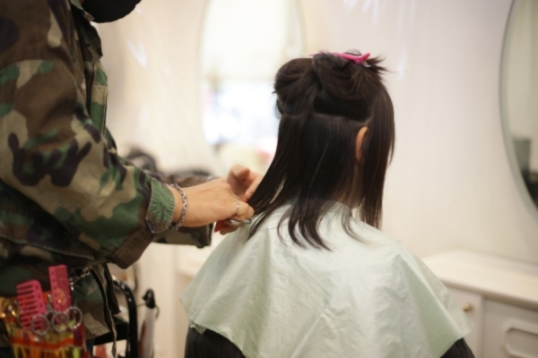 Repairing Heat‑Damaged Hair Hairdresser trimming the ends of a woman’s partially sectioned hair in a salon, a common step in managing and repairing heat-damaged hair by removing split ends.