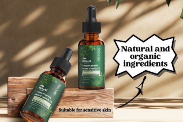 Two bottles of Mayraki CopperGro Pro Beard Growth Oil are displayed on a wooden block with promotional text reading “Natural and organic ingredients” and “Suitable for sensitive skin.” The setting is bright and minimal, reinforcing a natural and clean product feel.